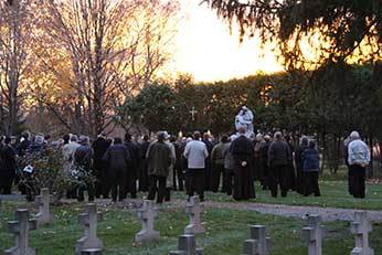 Holy Cross men praying at the Community Cemetery