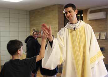 Deacon Chris Rehagen, CSC giving a high five to a Christ the King student