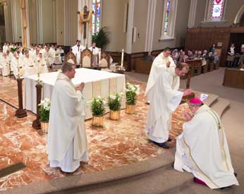 Newly ordained Mark DeMott, CSC giving the Bishop a blessing