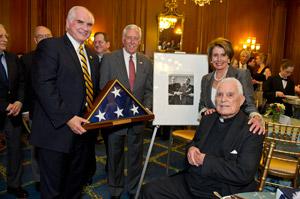Congressmen Mike Kelly and Steny Hoyer, and House Democrat Leader Nancy Pelosi present Father Hesburgh with an American flag