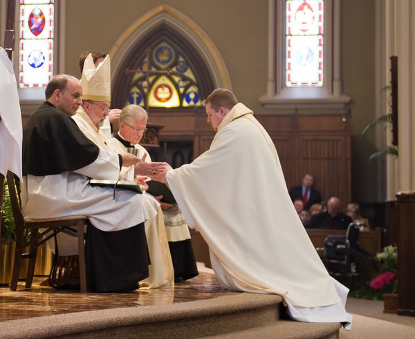Bishop Jenky, CSC anoints Rev Jarrod Waugh, CSC's hands with oil