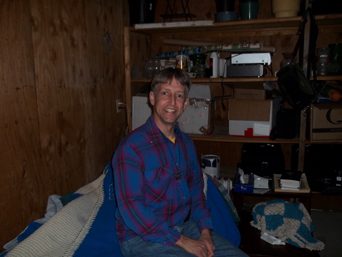 Fr Eric Schimmel sitting on a bed in the garage