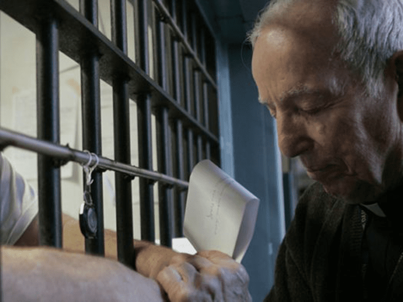 Fr. Tom McNally, C.S.C., prays with an inmate on death row