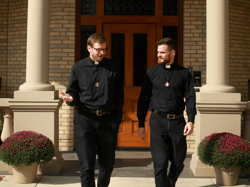 Two priests walking out of Corby Hall