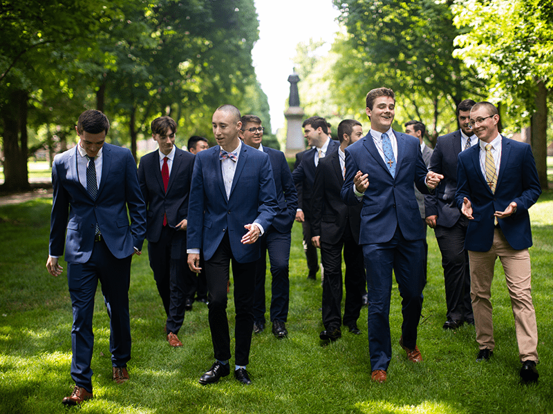 Old Collegians and Postulants walking together on the grass of Notre Dame's campus