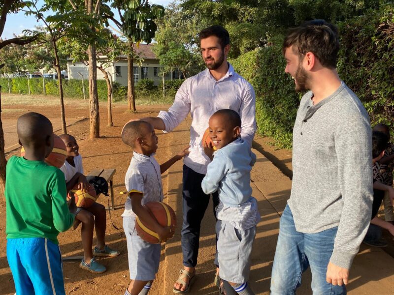 men holding basketballs with children