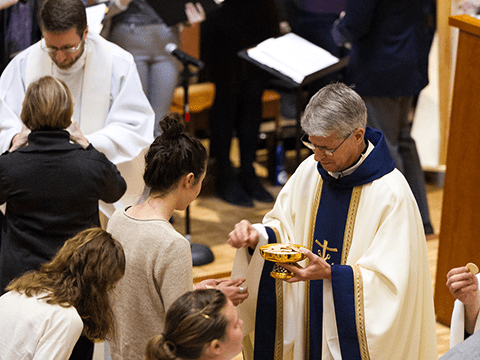CSC priest gives communion to a young parishioner
