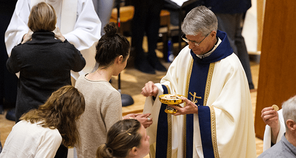 CSC priest gives communion to a young parishioner