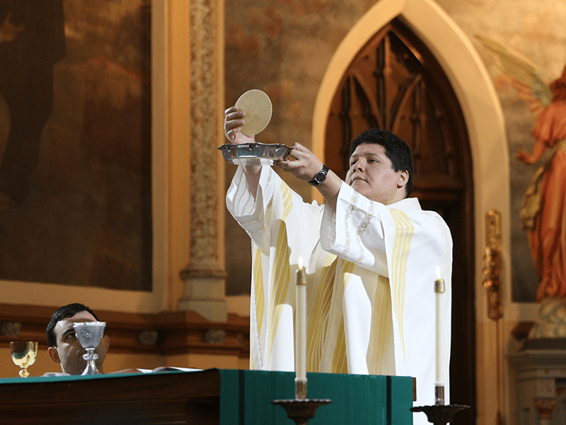 Fr. Paul Ybarra raises consecrated host