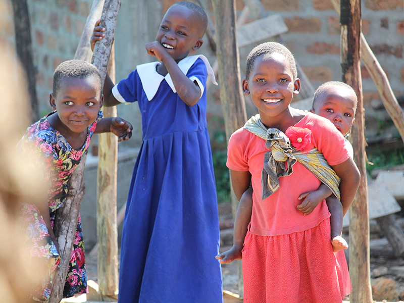 Children smiling and holding baby