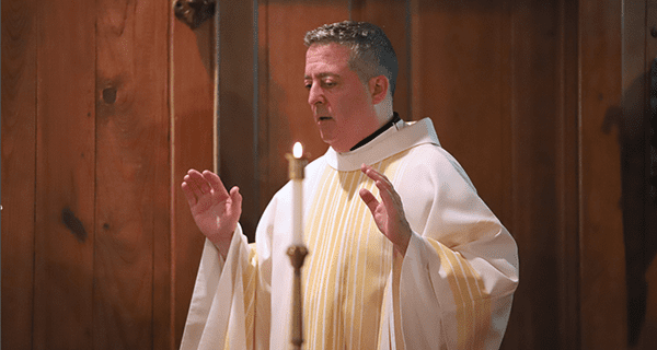 Father John DeRiso, CSC at a Log Chapel Mass