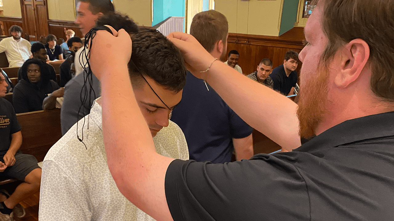 A coach at King's College bestows a medal on a football player