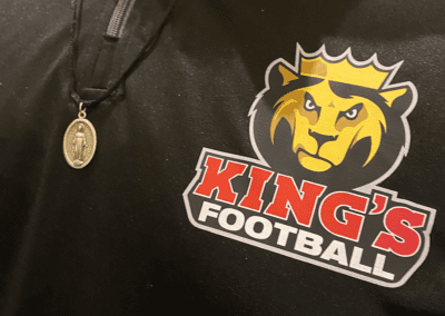 King's College football player polo with Miraculous Medal