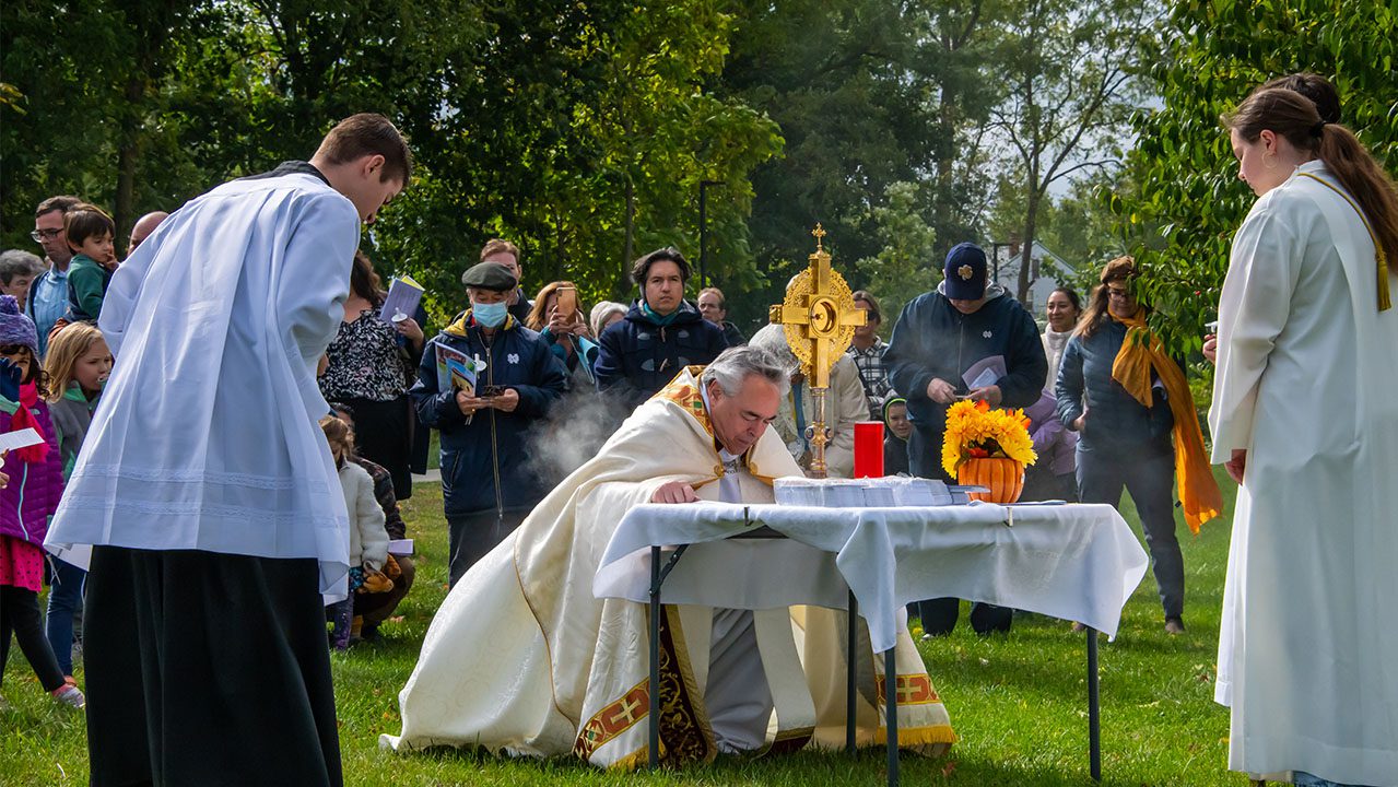 Fr. Jim Fenstermaker, CSC, bows before Eucharist during Holy Cross Parish’s Eucharistic Procession in 2023