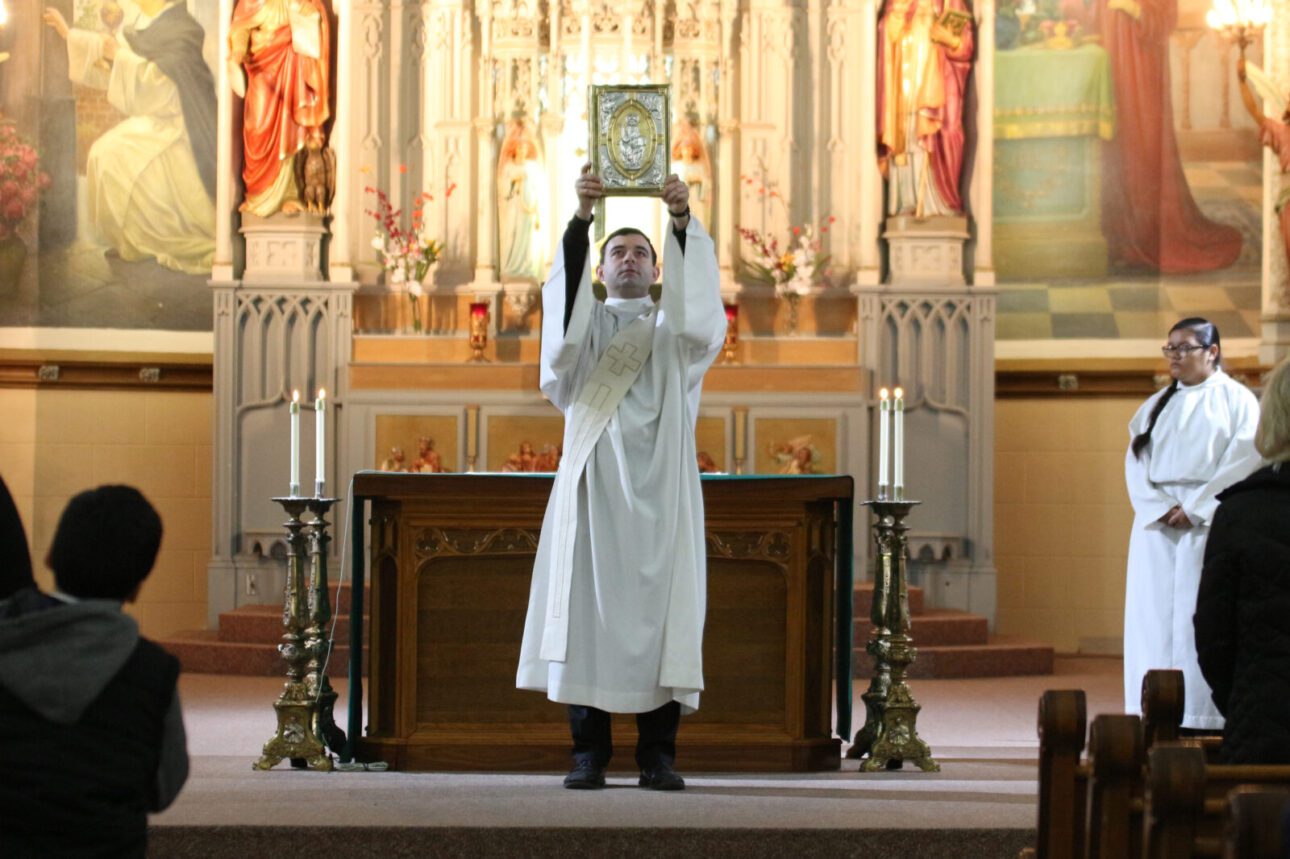 Holy Cross priest holding up the Gospel