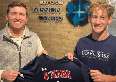 two men smiling and holding up a shirt