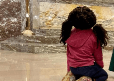 Child looking up while kneeling at Adoration