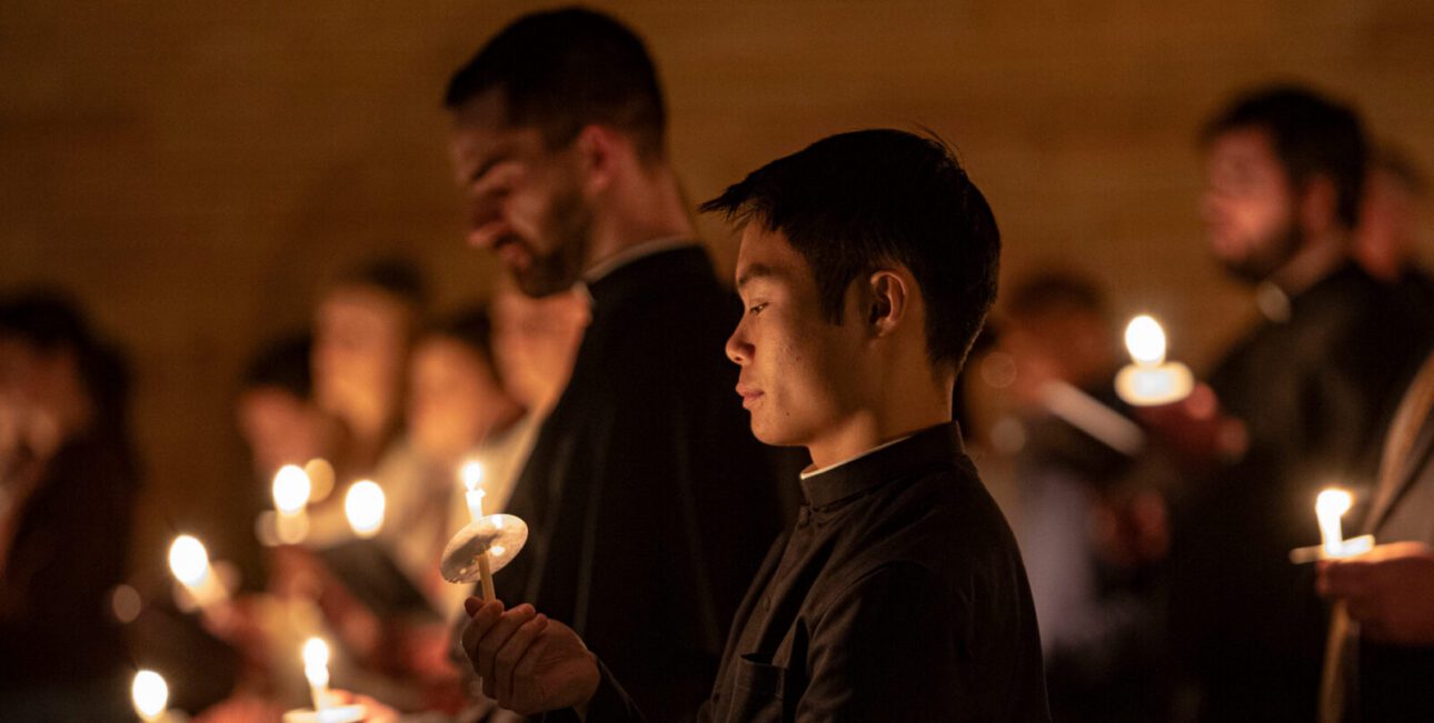 Br Jordan Chang holding a lit candle, participating in Lucernarium at Moreau Seminary and Scholasticate.