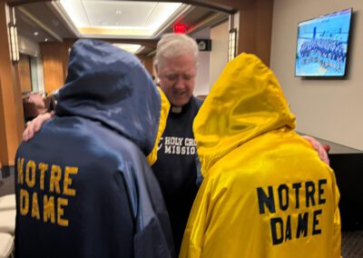Fr. Tom Eckert, C.S.C., extends his hands over two young men in prayer before the 2026 Bengal Bouts match.