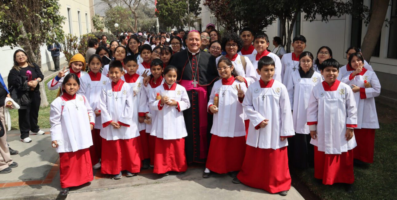 Bishop Jorge Izaguirre and poses outdoors with a group of young students after Mass. 