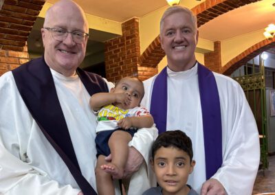 Fr. Bill Lies, C.S.C., and Fr. Tom Eckert, C.S.C., pose with an infant boy and his young brother at Mass