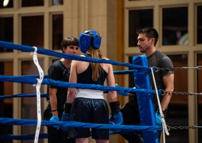 University of Notre Dame female boxing student stands in the ring and spars with male trainers.