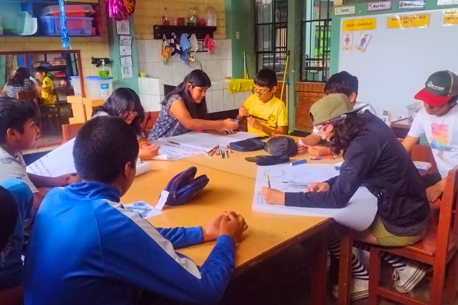 Group of people are seated around a table, drawing at Yancana Huasy during a workshop